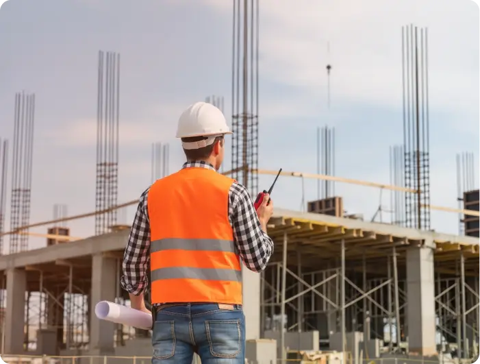 Engenheiro no canteiro de obras com planta e rádio